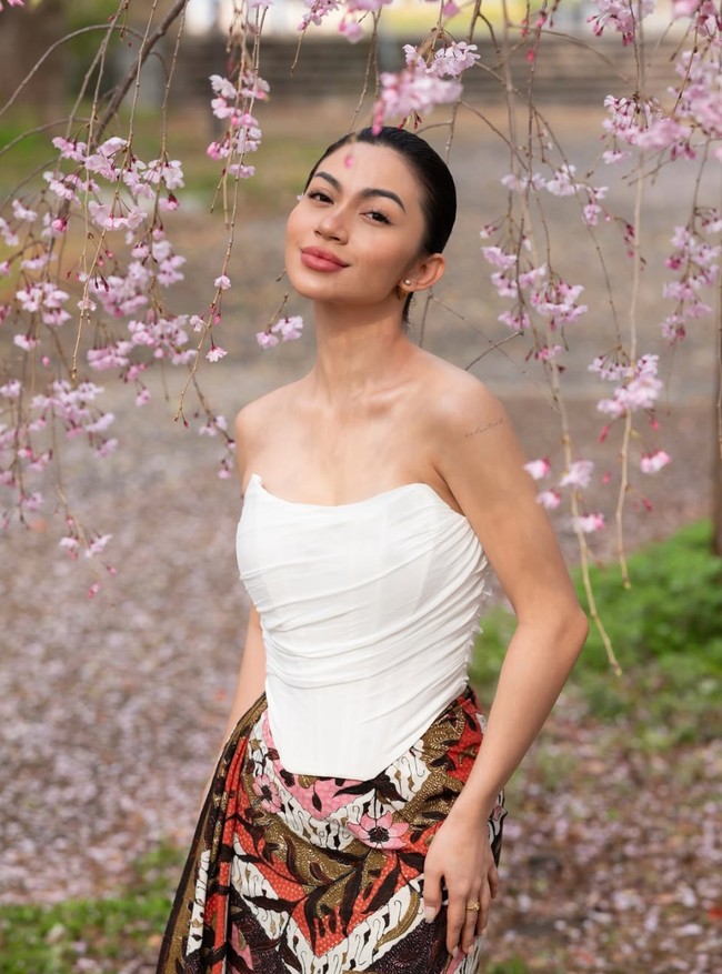 Berpose dikelilingi bunga Sakura berwarna merah muda yang sedang bermekaran, Ariel tatum terlihat cantik dan anggun. Aksesori yang dikenakannya juga tampak simpel, hanya sepasang anting tusuk berukuran kecil dan cincin. Foto: Instagram/@arieltatum