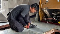 Teknisi Batam Aero Technic (BAT) melakukan pengecekan pada area lantai kabin pesawat Airbus A330 untuk memastikan kondisi lantai tetap aman dan bebas dari kerusakan. Pemeriksaan ini mencakup pengecekan kebersihan, keutuhan material lantai, serta fungsionalitas sistem penahan dan pelindung lantai, guna menjaga kenyamanan dan keamanan jemaah haji selama penerbangan.