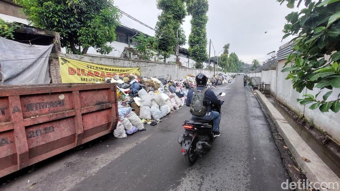 Warga Melintasi Jalan yang Dipenuhi Tumpukan Sampah di Jalan Djoyodikromo