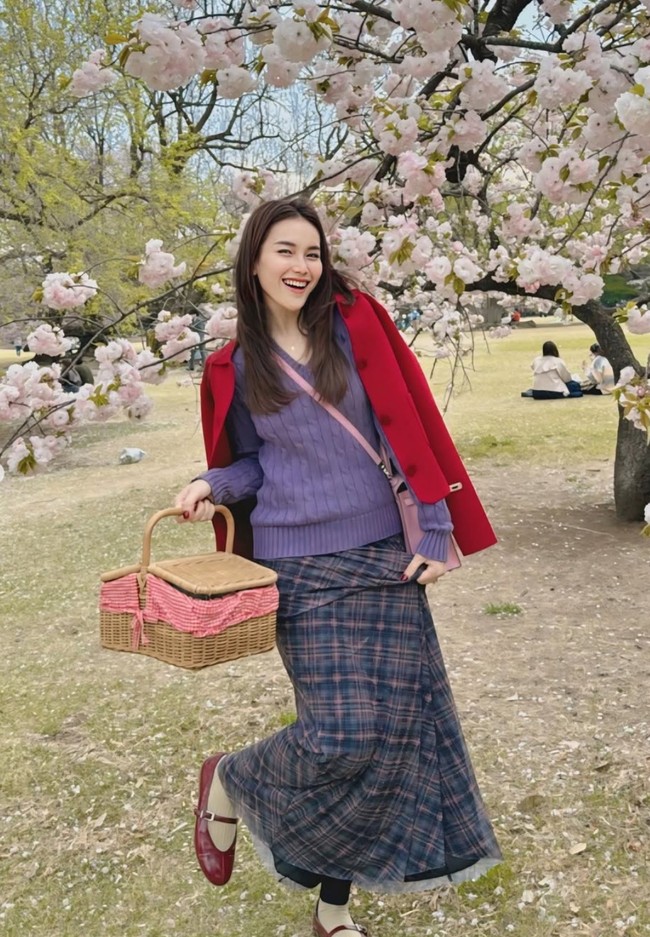 Di lain kesempatan Ayu memadukan tas Hermes pink miliknya dengan busana berwarna cerah kala berpose dengan latar belakang bunga Sakura. Sweater berwarna ungu dipadukannya dengan jaket merah dan rok panjang kotak-kotak. Foto: Instagram/@ayutingting92