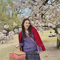 Di lain kesempatan Ayu memadukan tas Hermes pink miliknya dengan busana berwarna cerah kala berpose dengan latar belakang bunga Sakura. Sweater berwarna ungu dipadukannya dengan jaket merah dan rok panjang kotak-kotak. Foto: Instagram/@ayutingting92