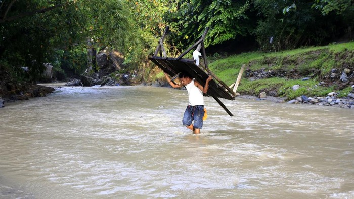 Warga menyeberangi sungai di Desa Pulubala, Kecamatan Pulubala, Kabupaten Gorontalo, Gorontalo, Selasa (15/4/2025). Warga terpaksa menerjang sungai agar dapat melintas dan beraktivitas dimana jembatan yang menghubungkan Kecamatan Pulubala, Tibawa dan Bongomeme tersebut ambruk.