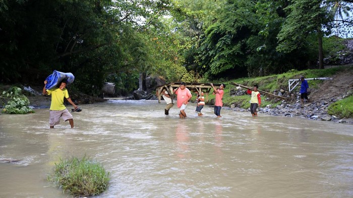 Warga menyeberangi sungai di Desa Pulubala, Kecamatan Pulubala, Kabupaten Gorontalo, Gorontalo, Selasa (15/4/2025). Warga terpaksa menerjang sungai agar dapat melintas dan beraktivitas dimana jembatan yang menghubungkan Kecamatan Pulubala, Tibawa dan Bongomeme tersebut ambruk.
