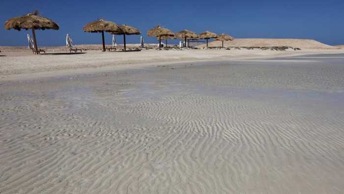 A man sits under a wooden structure at Ras Hankorab beach, home to one of the country's last untouched marine ecosystems, with crystal clear waters and white sands, at southern Egypt's Red Sea coast in Marsa Alam, Egypt March 23, 2025. REUTERS/Stringer     TPX IMAGES OF THE DAY