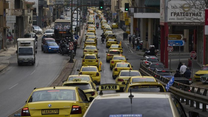 Taxi drivers drive their vehicles along a central road to protest against regulations affecting their industry during a one day strike in Athens, Greece, Tuesday, April 15, 2025.(AP Photo/Petros Giannakouris)
