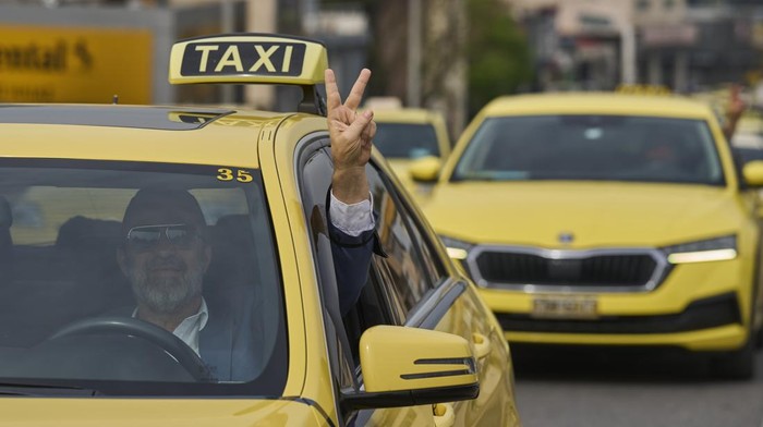 Taxi drivers drive their vehicles along a central road to protest against regulations affecting their industry during a one day strike in Athens, Greece, Tuesday, April 15, 2025.(AP Photo/Petros Giannakouris)