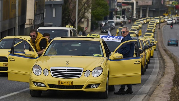 Taxi drivers drive their vehicles along a central road to protest against regulations affecting their industry during a one day strike in Athens, Greece, Tuesday, April 15, 2025.(AP Photo/Petros Giannakouris)
