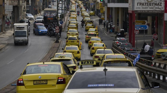 Taxi drivers drive their vehicles along a central road to protest against regulations affecting their industry during a one day strike in Athens, Greece, Tuesday, April 15, 2025.(AP Photo/Petros Giannakouris)
