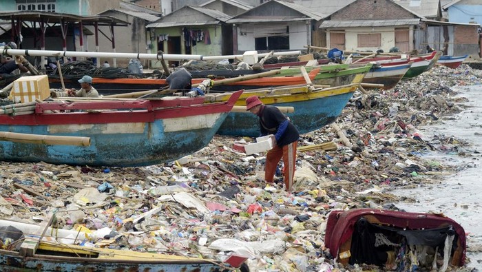 Nelayan melintasi tumpukan sampah di pesisir pantai Bandar Lampung, Lampung, Rabu (16/4/2025). Menurut warga setempat sampah yang menumpuk menutupi pesisir pantai itu sebagian besar berasal dari limbah rumah tangga yang terseret arus sungai saat musim hujan sehingga mencemari kawasan pantai. ANTARA FOTO/Ardiansyah/wpa.