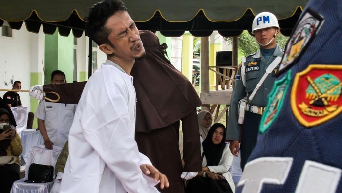 Terpidana pelanggar hukum syariat Islam (kiri) menahan sakit saat dicambuk algojo di Lhokseumawe, Aceh, Rabu (16/4/2025). Mahkamah Syar'yiah menjatuhkan hukuman 10-100 kali cambuk kepada sepuluh warga yang terbukti bersalah melakukan pelanggaran hukum Jinayat Qanun Syariat tentang Khalwat (zina) dan Maisir (judi). ANTARA FOTO/Rahmad/Spt.