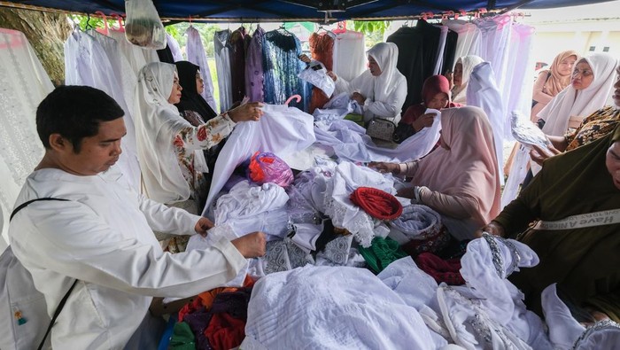 Seorang jamaah calon haji mencoba aksesoris haji yang dijual di area Asrama Haji Kendari, Sulawesi Tenggara, Kamis (17/4/2025). Pedagang musiman tersebut menyediakan berbagai jenis aksesoris seperti penutup kepala, pakaian dalam hingga kaos kaki dan sarung tangan untuk kebutuhan jamaah calon haji yang akan melaksanakan ibadah haji di Arab Saudi. ANTARA FOTO/Andry Denisah/foc.