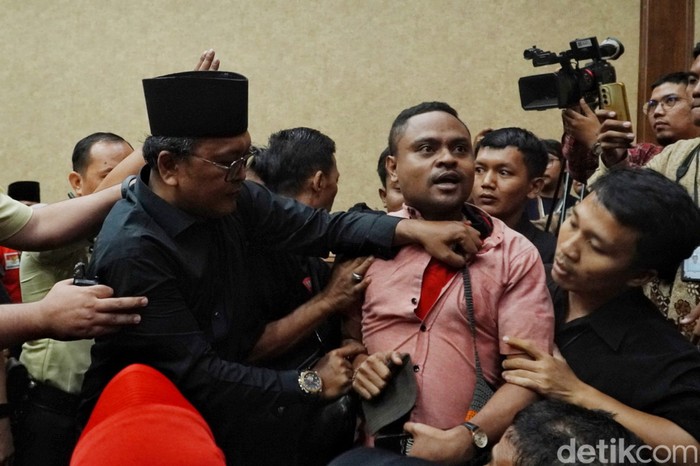 Dianggap Penyusup, Pria Ini Diusir dari Sidang Hasto Seorang pria berkaos merah bertuliskan #SaveKPKAdiliHasto diusir dari ruangan sidang dengan terdakwa Hasto Kristiyanto di Pengadilan Tipikor Jakarta Pusat, Kamis (17/5/2025). Peristiwa tersebut terjadi sebelum proses persidangan berlangsung atau sedang menunggu kehadiran hakim. Pihak yang mengusir menuding pria tersebut sebagai penyusup.