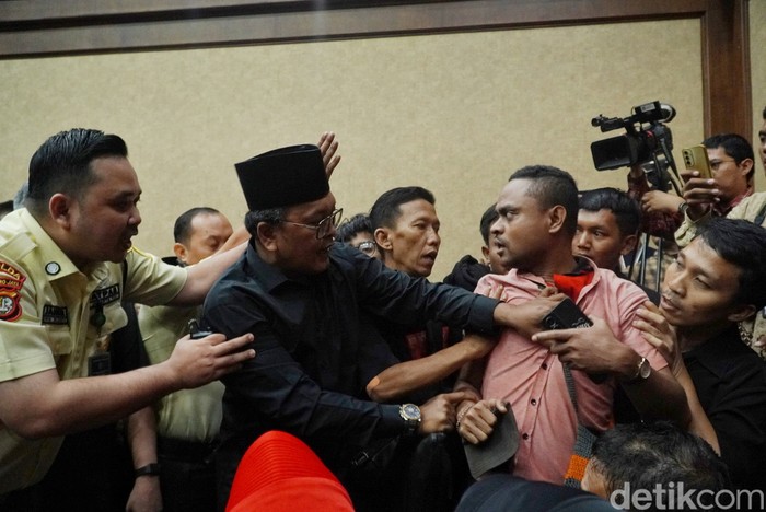 Seorang pria berkaos merah bertuliskan #SaveKPKAdiliHasto diusir dari ruangan sidang dengan terdakwa Hasto Kristiyanto di Pengadilan Tipikor Jakarta Pusat, Kamis (17/5/2025). Peristiwa tersebut terjadi sebelum proses persidangan berlangsung atau sedang menunggu kehadiran hakim. Pihak yang mengusir menuding pria tersebut sebagai penyusup.