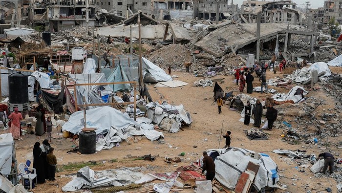 Penampakan Tenda-tenda Pengungsi Palestina Hancur Diserang Israel A Palestinian man inspects the damage at the site of an Israeli strike on a tent camp sheltering displaced people, in Khan Younis in the southern Gaza Strip April 17, 2025. REUTERS/Hatem Khaled