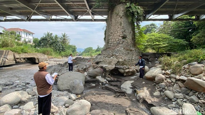 Petugas memeriksa kondisi pondasi jembatan Kali Keruh yang kritis akibat gerusan air, Kamis (17/4/2025).
