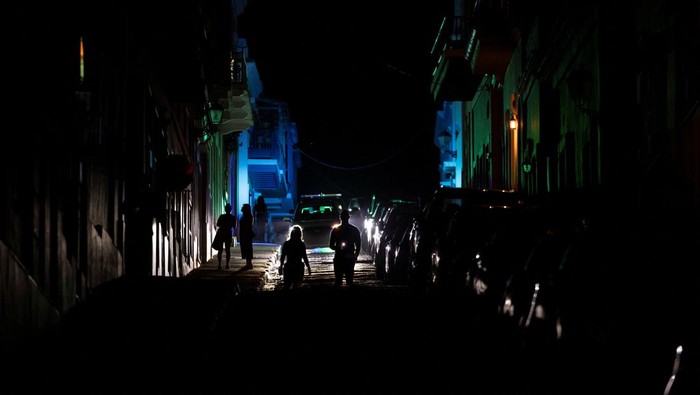 Puerto Riko Gelap Gulita Dilanda Mati Lampu Besar-besaran A couple take a selfie in front of a Puerto Rican flag after the country was hit with a massive power outage where energy plants across the island unexpectedly shut down, in San Juan, Puerto Rico April 16, 2025. REUTERS/Ricardo Arduengo TPX IMAGES OF THE DAY