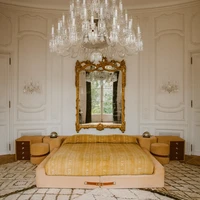Lampu gantung dan cermin berbingkai emas menciptakan atmosfer dramatis di kamar utama. Untuk menyeimbangkannya, ayah aktris Zoe Kravitz ini memilih tempat tidur yang minimalis.  (Foto: Architectural Digest/Matthieu Salvaing)