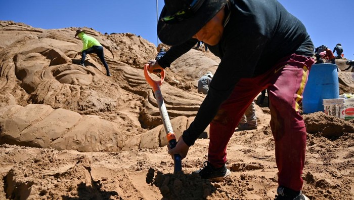 Aksi Seniman Memahat Adegan Alkitab di Bukit Pasir Bolivia An Aymara woman looks on as visual artists work on a sand sculpture depicting biblical scenes during Holy Week celebrations at the Arenales of Cochiraya, on the outskirts of Oruro, Bolivia April 18, 2025. REUTERS/Claudia Morales TPX IMAGES OF THE DAY
