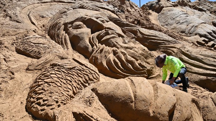 An Aymara woman looks on as visual artists work on a sand sculpture depicting biblical scenes during Holy Week celebrations at the Arenales of Cochiraya, on the outskirts of Oruro, Bolivia April 18, 2025. REUTERS/Claudia Morales     TPX IMAGES OF THE DAY