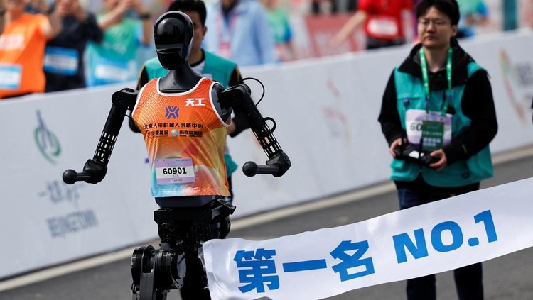 Engineers run with the humanoid robot as it participates along with human runners in the E-Town Half Marathon & Humanoid Robot Half Marathon in Beijing, China April, 19 2025. REUTERS/Tingshu Wang