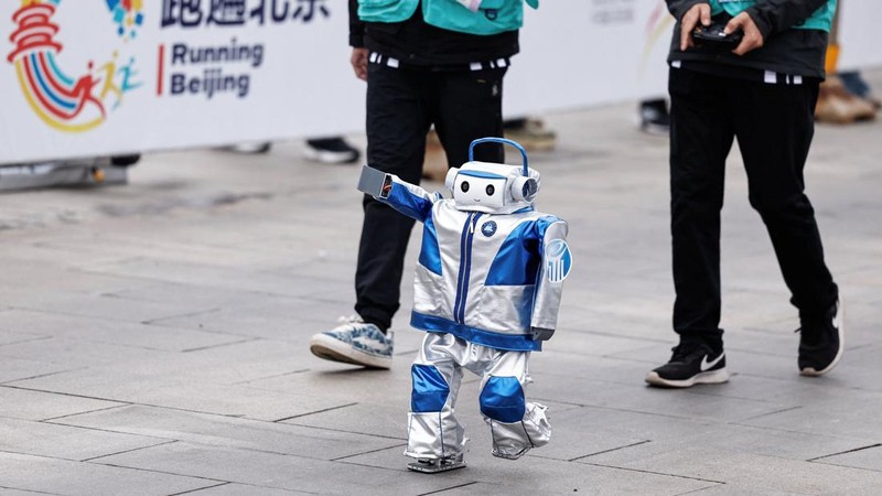 Engineers run with the humanoid robot as it participates along with human runners in the E-Town Half Marathon & Humanoid Robot Half Marathon in Beijing, China April, 19 2025. REUTERS/Tingshu Wang