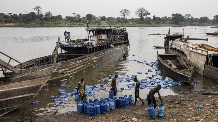 Workers unload gas cylinders from a boat coming from the Democratic Republic of Congo (DRC) on the Ubangui River in Bangui, on March 5, 2025. (Photo by PATRICK MEINHARDT / AFP)