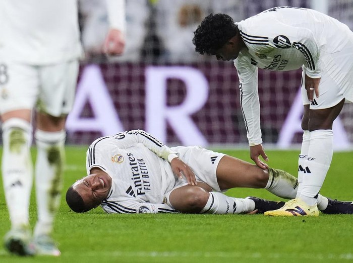 Real Madrid's Kylian Mbappe grimaces on the ground after getting injured during the Champions League quarterfinals second leg soccer match between Real Madrid and Arsenal at the Santiago Bernabeu stadium in Madrid, Wednesday, April 16, 2025. (AP Photo/Manu Fernandez)