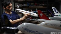 Seorang pekerja memperlihatkan model miniatur pesawat yang siap di kirim ke pelanggan di Singapura.