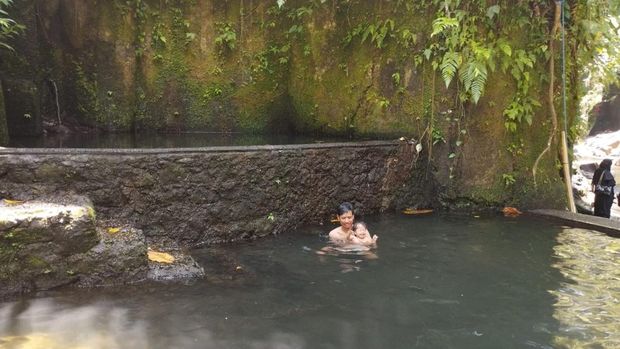 Wisatawan berendam di kolam di kawasan Air Terjun Kantolampo, Gianyar, Bali, Senin (12/4/2025).