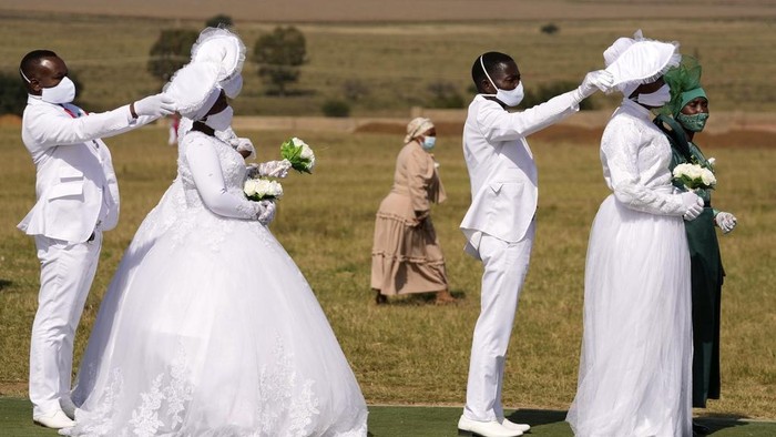 A man with his wife and two of his brides sits inside a marquee ahead of the mass Easter weddings for 3,000 people, some polygamous, at the International Pentecost Holiness Church in Heidelberg, east of Johannesburg, South Africa, Sunday, April 20, 2025. (AP Photo/Themba Hadebe)