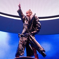 Dalam salah satu bagian paling teatrikal dari set panggungnya, pelantun lagu ‘Born Again’ ini memakai jaket puffer raksasa mengilap di atas bodysuit merah tersebut. Dia tampak berdiri gagah di atas platform tinggi, dengan rantai besar melingkar di pinggangnya, menambah kesan panggung yang megah dan intens. Foto: Getty Images