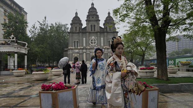 Women in traditional costumes past by the Wangfujing Catholic Church also know as East Church in Beijing, Monday, April 21, 2025. (AP Photo/Ng Han Guan)