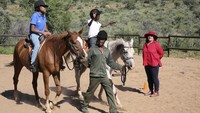 Susan de Meyer, kanan, dan Immanuel Hoxobeb membantu anak-anak yang berpartisipasi dalam program terapi Enabling Through the Horse di luar Windhoek, Namibia.