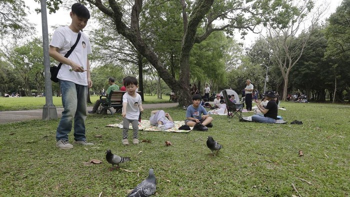 People rest on the lawn during a pre-Earth Day event in Taipei, Taiwan, Sunday, April 20, 2025, ahead of its April 22 annual event. (AP Photo/Chiang Ying-ying)
