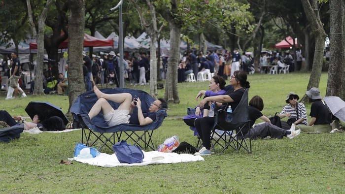 People rest on the lawn during a pre-Earth Day event in Taipei, Taiwan, Sunday, April 20, 2025, ahead of its April 22 annual event. (AP Photo/Chiang Ying-ying)