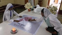 Para biarawati Katolik dari Misionaris Cinta Kasih, ordo yang didirikan oleh Santa Teresa, menyentuh potret Paus Fransiskus saat berdoa di makam di Kolkata, India, Selasa (22/4/2025).