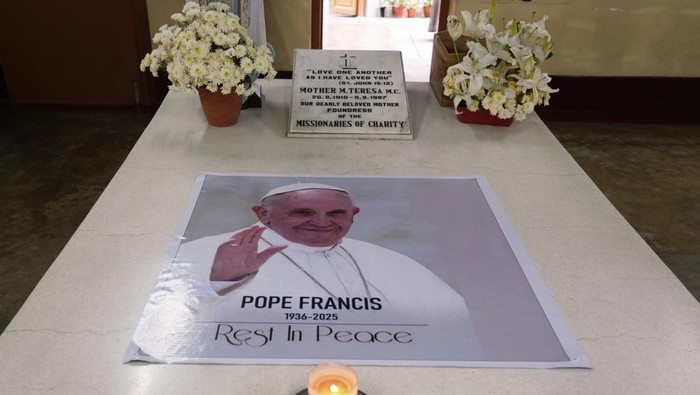 A Catholic nun of the Missionaries of Charity, the order founded by Saint Teresa, prays as a portrait of Pope Francis is placed over the tomb following his death, in Kolkata, India, Tuesday, April 22, 2025. (AP Photo/Bikas Das)