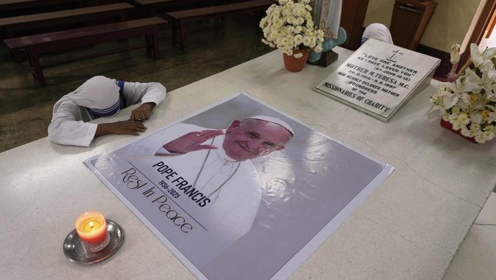 A Catholic nun of the Missionaries of Charity, the order founded by Saint Teresa, prays as a portrait of Pope Francis is placed over the tomb following his death, in Kolkata, India, Tuesday, April 22, 2025. (AP Photo/Bikas Das)