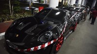 Petugas memasang garis pengaman pada mobil yang disita penyidik Kejagung di Gedung Kejaksaan Agung, Jakarta, Senin (21/4/2025) malam. 
