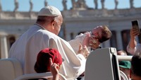 Paus Fransiskus membelai seorang anak saat tiba di Lapangan Santo Petrus untuk memimpin audiensi umum mingguan di Kota Vatikan, pada 26 Juni 2024. Massimo Valicchia/NurPhoto via Getty Images