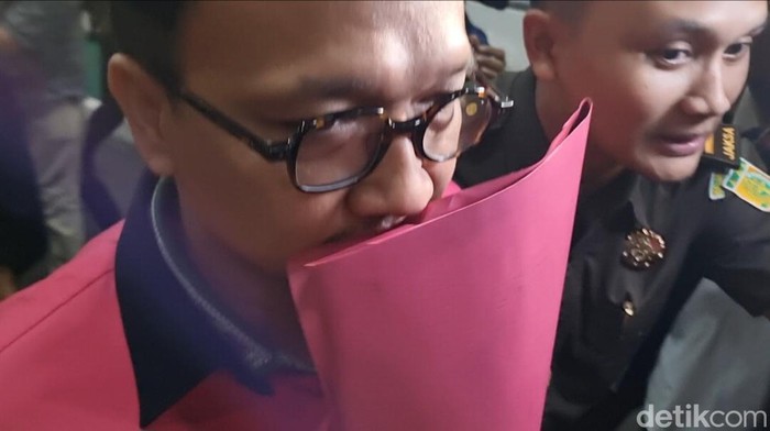 Tian Bahtiar (TB) (pakai masker) dan Junaedi Saibih (JS) (tutupi wajah dengan map)