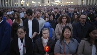 Umat beriman berkumpul untuk berdoa rosario bagi mendiang Paus Fransiskus, di Lapangan Santo Petrus di Vatikan, Senin (21/4/2025). Umat Katolik di seluruh dunia merespons dengan duka mendalam. Di Lapangan Santo Petrus, ribuan umat berkumpul untuk berdoa Rosario sebagai penghormatan terakhir. AP/Alessandra Tarantino