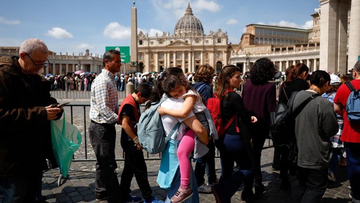 A woman with a child queues to enter St. Peters Basilica at the Vatican to pay respects to the late Pope Francis after the translation of his body and its transfer to the basilica, as seen from Rome, Italy, April 23, 2025. REUTERS/Susana Vera REFILE - CORRECTING LOCATION FROM AT THE VATICAN TO AS SEEN FROM ROME.