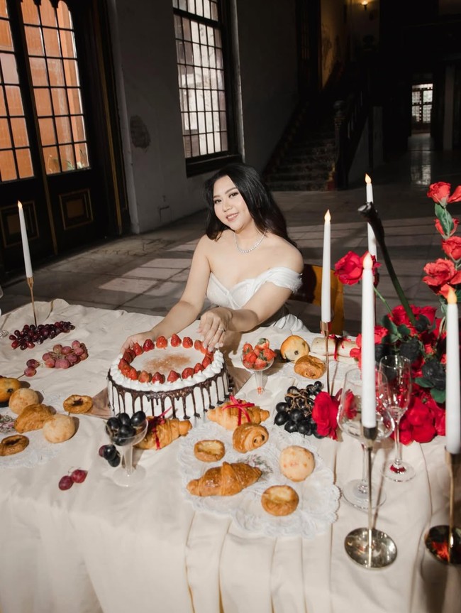 Dekorasi di sesi pemotretan tersebut dibuat unik dengan meja panjang yang dipenuhi croissant, buah, dan bunga mawar merah. Di bagian tengah-tengahnya juga terdapat sebuah kue tart, membuat sesi pemotretan kian terlihat elegan. Foto: Instagram/@celloszxz