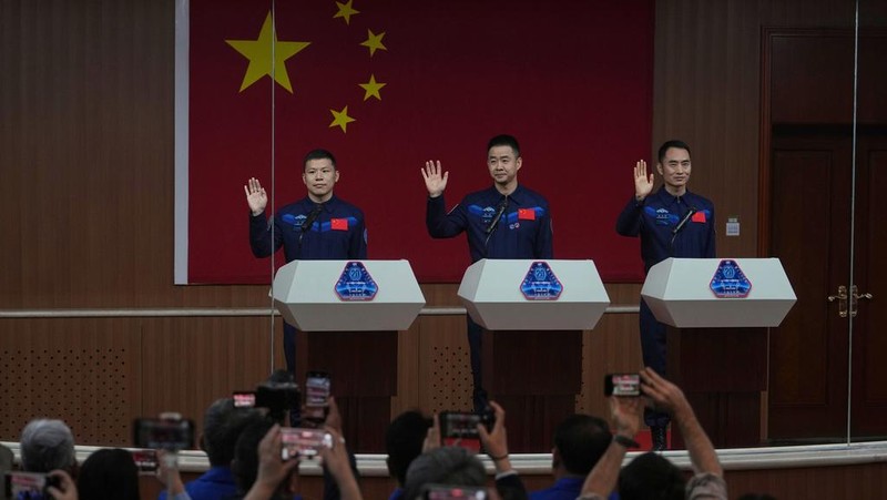 Journalists film Chinese astronauts for the upcoming Shenzhou 20 mission, from left, Wang Jie, captain Chen Dong and Chen Zhongrui wave at the Jiuquan Satellite Launch Center in northwest China, Wednesday, April 23, 2025. (AP Photo/Andy Wong)