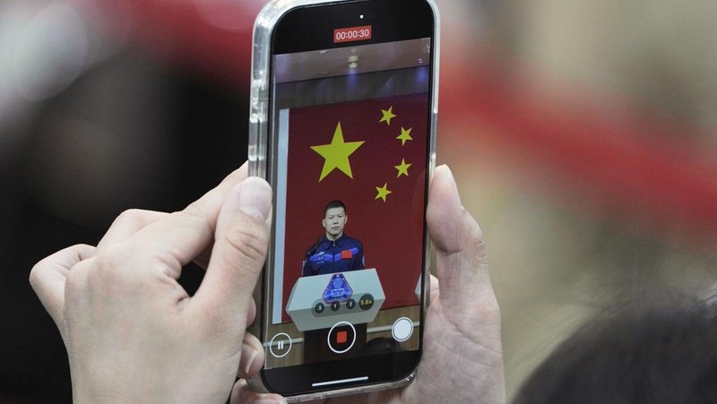 Journalists film Chinese astronauts for the upcoming Shenzhou 20 mission, from left, Wang Jie, captain Chen Dong and Chen Zhongrui wave at the Jiuquan Satellite Launch Center in northwest China, Wednesday, April 23, 2025. (AP Photo/Andy Wong)