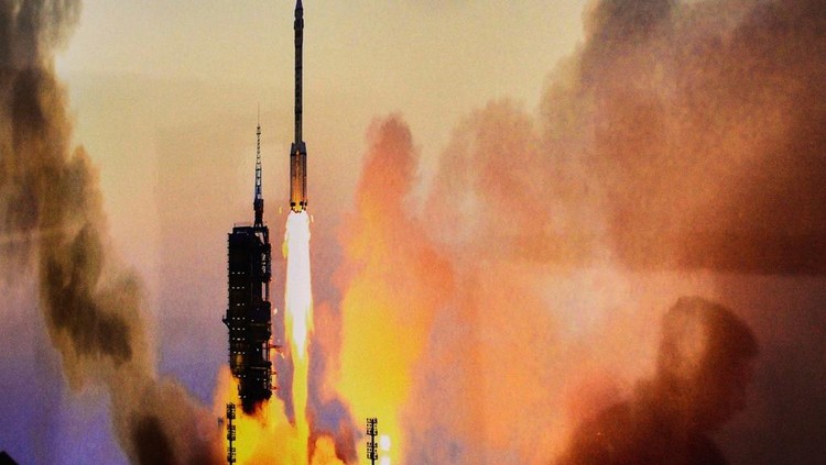 Journalists film Chinese astronauts for the upcoming Shenzhou 20 mission, from left, Wang Jie, captain Chen Dong and Chen Zhongrui wave at the Jiuquan Satellite Launch Center in northwest China, Wednesday, April 23, 2025. (AP Photo/Andy Wong)
