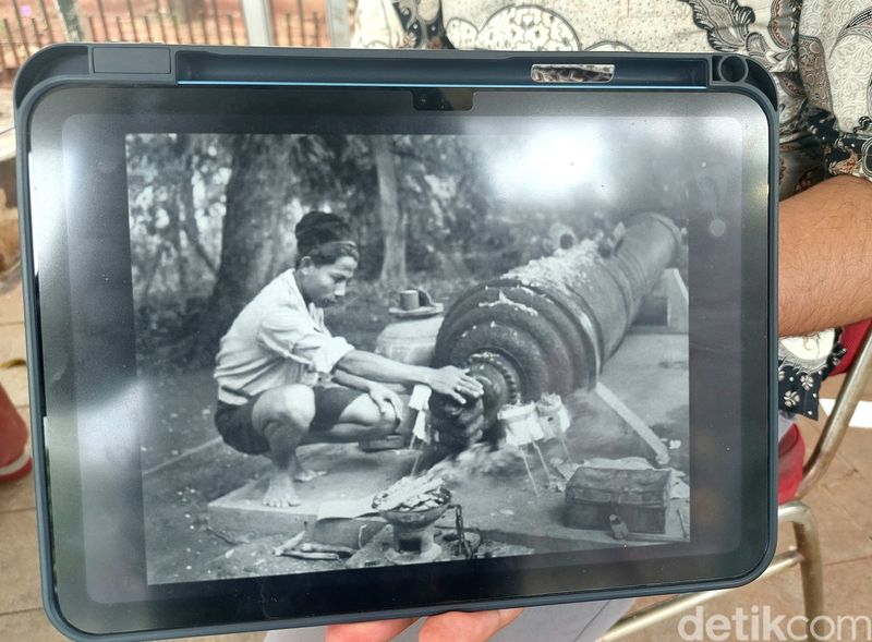 Foto lama yang memperlihatkan seorang pria melakakn ritual dengan menyentuh simbol jempol kejepit di Meriam Si Jagur