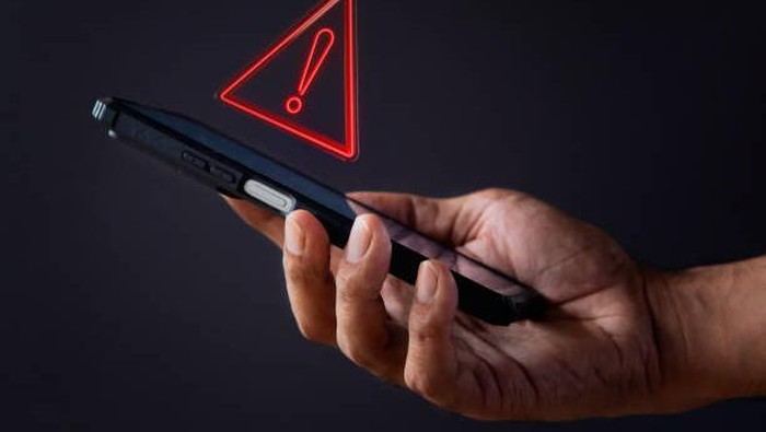 Smartphone with triangle caution warning icon. System error, malware and cyber crime concept.