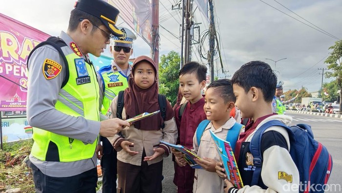 Kapolresta Magelang Kombes Herbin Garbawiyata Jaya Sianipar saat membagikan komik kepada siswa SD Negeri Blondo, Rabu (23/4/2025).